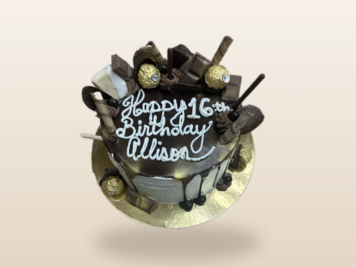 Chocolate birthday cake decorated with chocolates and gold accents